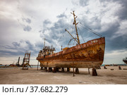 Mangystau, Kazakhstan - May 19, 2012: Bautino bay. Old rusted ship on Caspian Sea ship-repairing yard. Grey storm cloudy sky. Стоковое фото, фотограф Alexey Rezvykh / Фотобанк Лори