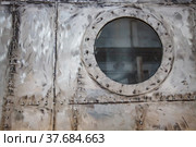 Ship-building plant. Scratched not painted metal cockpit with glass port-hole illuminator. Стоковое фото, фотограф Alexey Rezvykh / Фотобанк Лори
