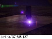 Laser cutting CNC machine. Blue laser beam and sparks. Dark tones photo background. Not underexposed. Стоковое фото, фотограф Alexey Rezvykh / Фотобанк Лори