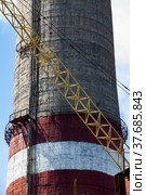 GRES-1 thermal power station. Close up photo of concrete smoke stack. Textured concrete, and yellow crane jib on foreground. Ekibastuz, Pavlodar region, Kazakhstan. Стоковое фото, фотограф Alexey Rezvykh / Фотобанк Лори