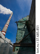 GRES-1 thermal power station. Grey raw coal bunkers and smoke stack with white smoke left. Boiler pipe with green thermal insulation right. Ekibastuz, Pavlodar region, Kazakhstan. Стоковое фото, фотограф Alexey Rezvykh / Фотобанк Лори