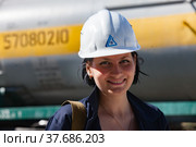 Caustic chemical plant. Attractive young engineer girl in white hardhat posing and smiling on railway tank wagon background. (2012 год). Редакционное фото, фотограф Alexey Rezvykh / Фотобанк Лори