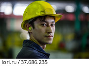 Pavlodar Aluminium electrolysis plant. Portrait of young Asian worker in yellow hardhat and yellow earplugs. (2012 год). Редакционное фото, фотограф Alexey Rezvykh / Фотобанк Лори