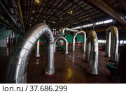 Aksu, Pavlodar region, Kazakhstan - May 29, 2012: Aksu steam power station workshop. Pipes with thermal insulation and shiny metal cover. Green electric machine, steam turbine and generator. Редакционное фото, фотограф Alexey Rezvykh / Фотобанк Лори