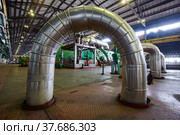 Aksu, Pavlodar region, Kazakhstan - May 29, 2012: Aksu steam power station workshop. Pipes with thermal insulation and shiny metal cover. Green electric machine, steam turbine and generator. Редакционное фото, фотограф Alexey Rezvykh / Фотобанк Лори