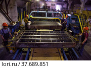 Temirtau, Kazakhstan - June 09, 2012: Concrete sleepers manufacturing plant NORD Prom NS. Vibration line machine and workers. Редакционное фото, фотограф Alexey Rezvykh / Фотобанк Лори