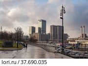 Moscow, Russia - November 20, 2020: Renovated Krasnopresnenskaya embankment. Office and apartment buildings of various architecture on autumn blue cloudy sky. Yellow light of sunset. WTC building. Редакционное фото, фотограф Alexey Rezvykh / Фотобанк Лори