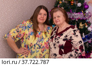 Радостные мама и дочка около новогодней елки в новогодние праздники. Joyful mom and daughter near the Christmas tree on New Year's holidays. (2022 год). Редакционное фото, фотограф Мария / Фотобанк Лори