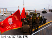Красное знамя развевается на ветру у мужчин в военной форме времен Великой Отечественной Войны (2022 год). Редакционное фото, фотограф Nikolay Pestov / Фотобанк Лори