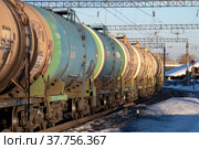 Проходящий грузовой поезд из цистерн для перевозки нефтепродуктов крупным планом мартовским днем (2022 год). Редакционное фото, фотограф Виктор Карасев / Фотобанк Лори
