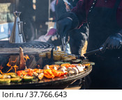 The cook cooks vegetables on the grill on the fire. Fish Festival in Svetlogorsk Raushen, Kalinigrad region, Russia, near the Baltic sea. Стоковое фото, фотограф Yuriy Savin / Фотобанк Лори