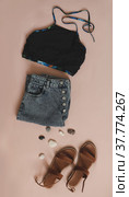 flat lay composition with female top, denim shorts, sandals and a wicker rattan bag on beige background top view. Стоковое фото, фотограф Galina kondratenko / Фотобанк Лори