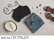 flat lay composition with female top, denim shorts, sandals and a wicker rattan bag on beige background top view. Стоковое фото, фотограф Galina kondratenko / Фотобанк Лори