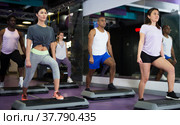 Group of people working out with steppers in fitness center. Стоковое фото, фотограф Яков Филимонов / Фотобанк Лори