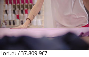 A woman designer works with purplish pink fabric by the table. Стоковое видео, видеограф Константин Шишкин / Фотобанк Лори
