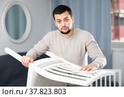 Young man wiping chair with duster at home. Стоковое фото, фотограф Яков Филимонов / Фотобанк Лори
