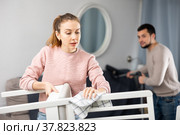 Young housewife wiping dust on furniture while man vacuuming. Стоковое фото, фотограф Яков Филимонов / Фотобанк Лори
