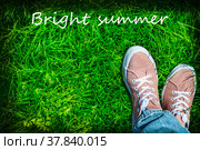 Ноги девушки в розовых кедах на фоне зеленой лужайки, надпись "Bright summer". Стильный, модный яркий летний фон. Радуемся лету, теплу, ярким краскам. В парке, непринужденная удобная обувь и стиль одежды, свобода, непосредственность. Фон, обои, открытка. Стоковое фото, фотограф Ludmila Zyubina / Фотобанк Лори