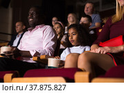 Mulatto tween girl eating popcorn and watching movie in cinema. Стоковое фото, фотограф Яков Филимонов / Фотобанк Лори