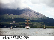 Парусник Nippon Maru с буксирами на фоне вулкана Сакурадзима (Кюсю, Япония) (2010 год). Стоковое фото, фотограф Александр Гаценко / Фотобанк Лори