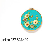 Hand embroidery of floral ornament with woolen threads on green canvas. The flowers are embroidered with a punched tapestry or carpet seam, leaves are with a tambour or chain stitch. Flat lay, copy space. Стоковое фото, фотограф Виктория Катьянова / Фотобанк Лори