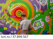 Посетитель разрисовывает стену на площадке фестиваля, посвященного Дню молодежи, в парке "Музеон" города Москвы, Россия (2022 год). Редакционное фото, фотограф Николай Винокуров / Фотобанк Лори