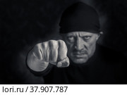 Мужчина наносит удар кулаком, фокус на переднем плане. Крупный план мужского кулака. Социальные темы, насилие в семье.  Черно-белая фотография, бытовое насилие. Стоковое фото, фотограф Виталий Михайлюк / Фотобанк Лори