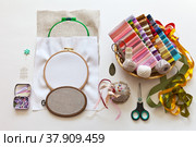 Accessories for hand embroidery with satin ribbons: various hoops, needles with large eye, needle threaders, pins, beads, scissors and sets of colorful ribbons on white background. DIY-cocept. Flat lay. Стоковое фото, фотограф Виктория Катьянова / Фотобанк Лори