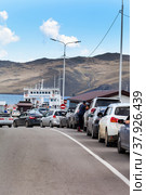 SAKHYURTA VILLAGE, MRS, BAIKAL LAKE, IRKUTSK REGION, RUSSIA - July 09, 2022: Cars with tourists stand in line for a ferry crossing to Olkhon Island - a favorite place for summer holidays. Редакционное фото, фотограф Виктория Катьянова / Фотобанк Лори