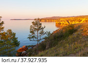 Baikal Lake. Coast of Olkhon Island. Summer sunset colored coastal cliffs in golden color. Beautiful landscape. Natural background. Стоковое фото, фотограф Виктория Катьянова / Фотобанк Лори