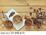 Cooking a nut mixture with honey. Peeled pine nuts and walnuts, a jar of honey and the cinnamon sticks on a wooden table. Delicious and healthy breakfast or snack. Flat lay, copy space, tp view, mock up. Стоковое фото, фотограф Виктория Катьянова / Фотобанк Лори