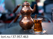 Turkish traditional tea in tulip-shaped glass with cupper colored double teapot. Стоковое фото, фотограф Юлия Паутова / Фотобанк Лори