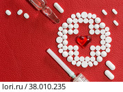 Белые таблетки, шприц и ампула лежат на поверхности красной искусственной кожи. Шаблон для рецепта. Стоковое фото, фотограф Борис Ряузов / Фотобанк Лори