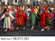 Люди в русских национальных костюмах водят хороводы и поют народные песни во время фестиваля Хороводы России на площади выставочного центра ВДНХ на фоне павильона № 1 "Центральный" в городе Москве, Россия (2022 год). Редакционное фото, фотограф Николай Винокуров / Фотобанк Лори