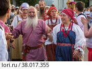 Люди в русских национальных костюмах водят хороводы и поют народные песни во время фестиваля Хороводы России на площади выставочного центра ВДНХ на фоне павильона № 1 "Центральный" в городе Москве, Россия (2022 год). Редакционное фото, фотограф Николай Винокуров / Фотобанк Лори