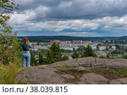 Девушка фотографирует город с горы Кухавуори парка Ваккосалми. Сортавала в Карелии (2022 год). Редакционное фото, фотограф Румянцева Наталия / Фотобанк Лори