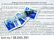 Шприц и спиртовые салфетки крупным планом на бланке добровольного информированного согласия на проведение профилактических прививок или отказа от них (2022 год). Редакционное фото, фотограф Анна Аникова / Фотобанк Лори