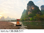China. The beautiful Li River (Lijiang River) with green karst hills along the banks at sunset. Traditional bamboo pleasure raft waiting for tourists on the stony beach (2011 год). Стоковое фото, фотограф Виктория Катьянова / Фотобанк Лори