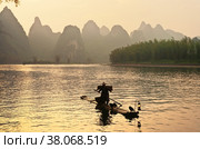 China. Xingping. Li River (Lijiang River) with karst hills at sunset . Silhouette of a fisherman on a bamboo raft with tame cormorant birds. Traditional way of fishing. Beautiful unusual landscape (2011 год). Стоковое фото, фотограф Виктория Катьянова / Фотобанк Лори
