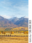 Beautiful rural autumnal landscape with yellowed meadows and haystacks against the background of Eastern Sayan Mountains with low clouds on a sunny day. Buryatia, Baikal region, Tunka Valley, Arshan. Стоковое фото, фотограф Виктория Катьянова / Фотобанк Лори