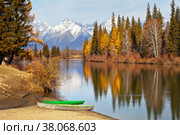 Admirable autumn landscape with yellowed trees and green boats on the banks of calm river at the background of snowy mountains at sunny day. Siberia, Baikal region, Eastern Sayan, Buryatia, Irkut river, Tunka valley, Стоковое фото, фотограф Виктория Катьянова / Фотобанк Лори
