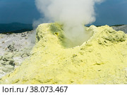 Cone of sulfur deposits around a fumarole in a solfataric field illuminated by the sun against a stormy landscape in the distance. Стоковое фото, фотограф Евгений Харитонов / Фотобанк Лори