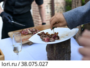 The chef cooks the veal at a plancha and the guest at the wedding tastes the meat. Стоковое фото, фотограф Irina Kuchugurina/Gaudy / Фотобанк Лори