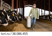 Farmer carrying milk churn near stall with cows in cowshed. Стоковое фото, фотограф Яков Филимонов / Фотобанк Лори