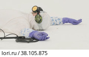 Man in white chemical protection suit holds metal detector. Стоковое видео, видеограф Aleksey Kidisyuk / Фотобанк Лори