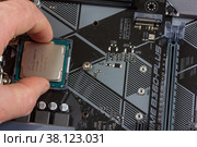 Maykop, Russia - November 9, 2018: man installs an 8th generation Intel core I3 processor into a motherboard socket. Редакционное фото, фотограф Андрей С / Фотобанк Лори