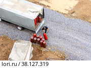 A man loads red gas cylinders into the body of a truck under an awning (2021 год). Редакционное фото, фотограф Дмитрий Коростылев / Фотобанк Лори