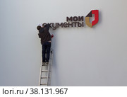 Рабочий прикрепляет на стену надпись "Мои документы". Москва (2021 год). Редакционное фото, фотограф Елена Орлова / Фотобанк Лори