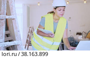Female foreman in a protective helmet and a yellow vest checks the execution of repair work using a laptop. Стоковое видео, видеограф Яков Филимонов / Фотобанк Лори