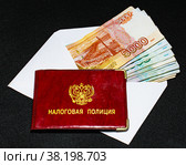 Удостоверение налоговой полиции на конверте с денежными купюрами на черном фоне (2022 год). Редакционное фото, фотограф Анна Аникова / Фотобанк Лори